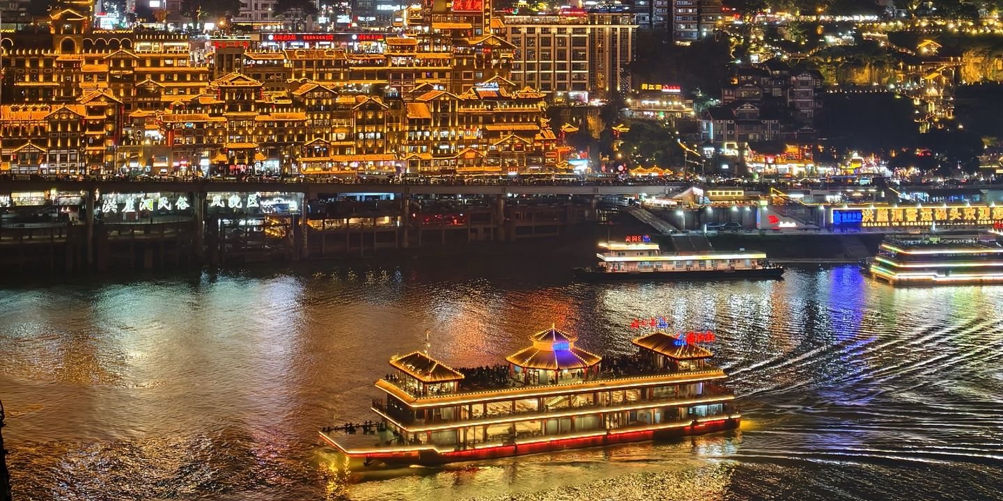 Illuminated night cruise ship on the river below Hongya Cave in Chongqing